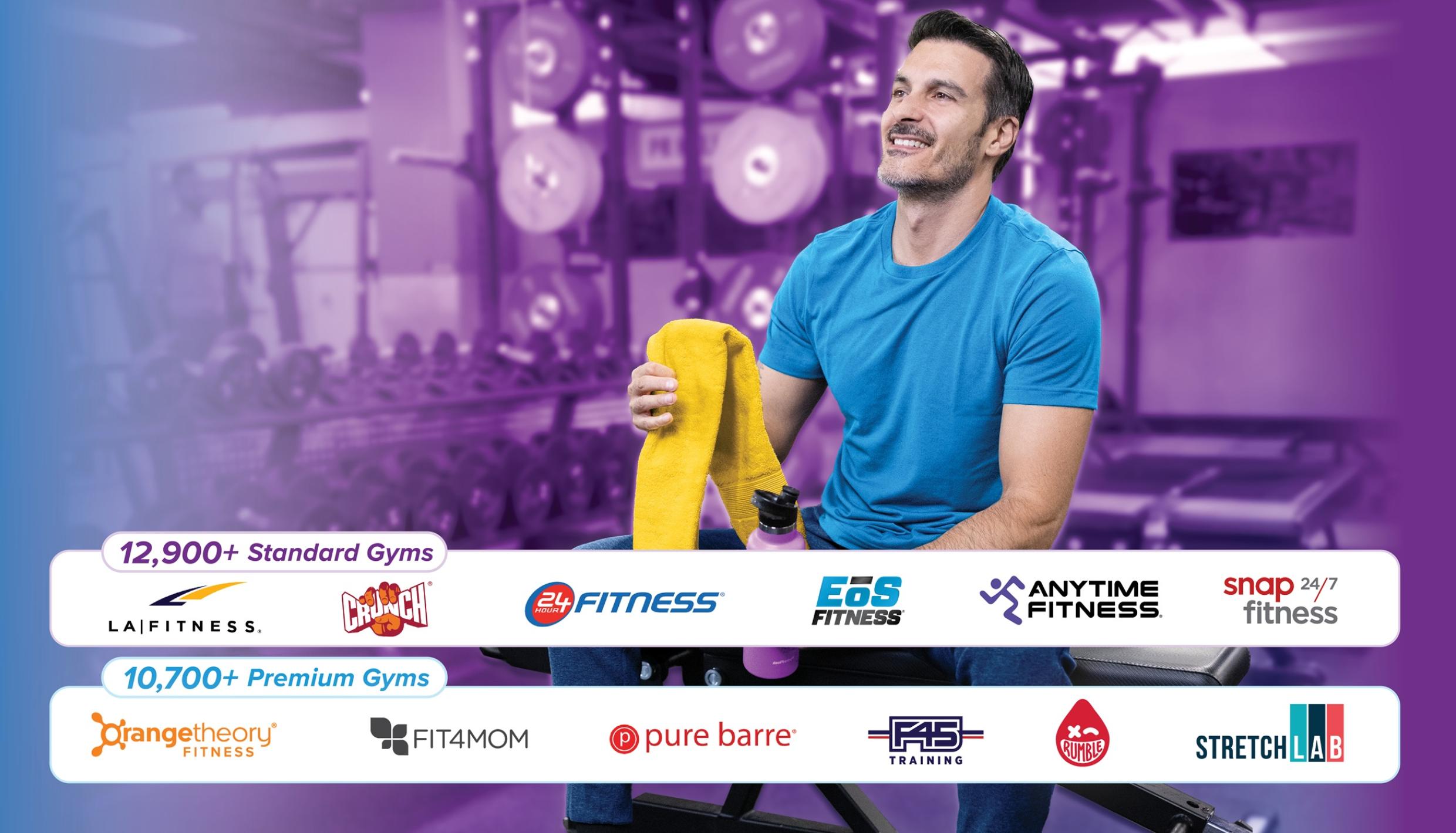 Man smiling holding towel in gym.