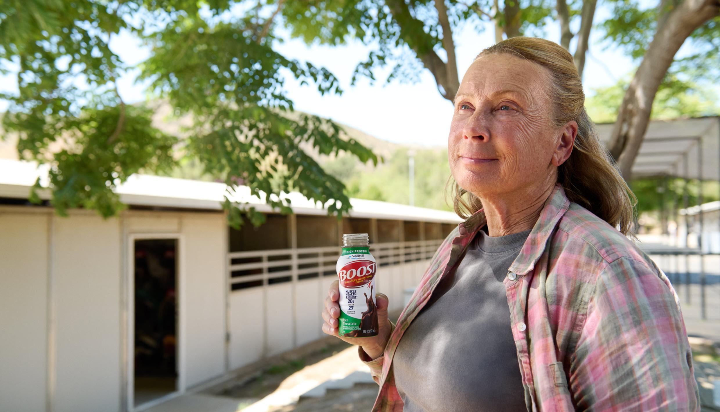 Mujer de pie al aire libre sosteniendo un batido Boost