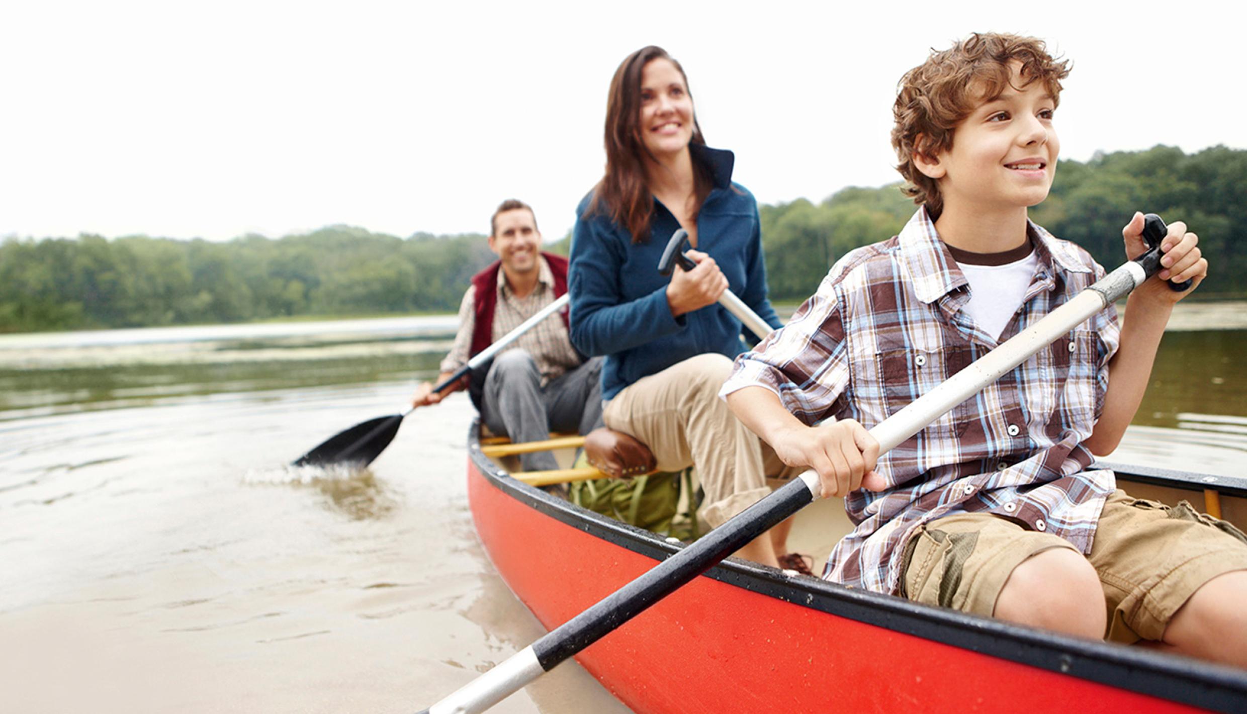 A family paddles in a canoe on a quiet lake