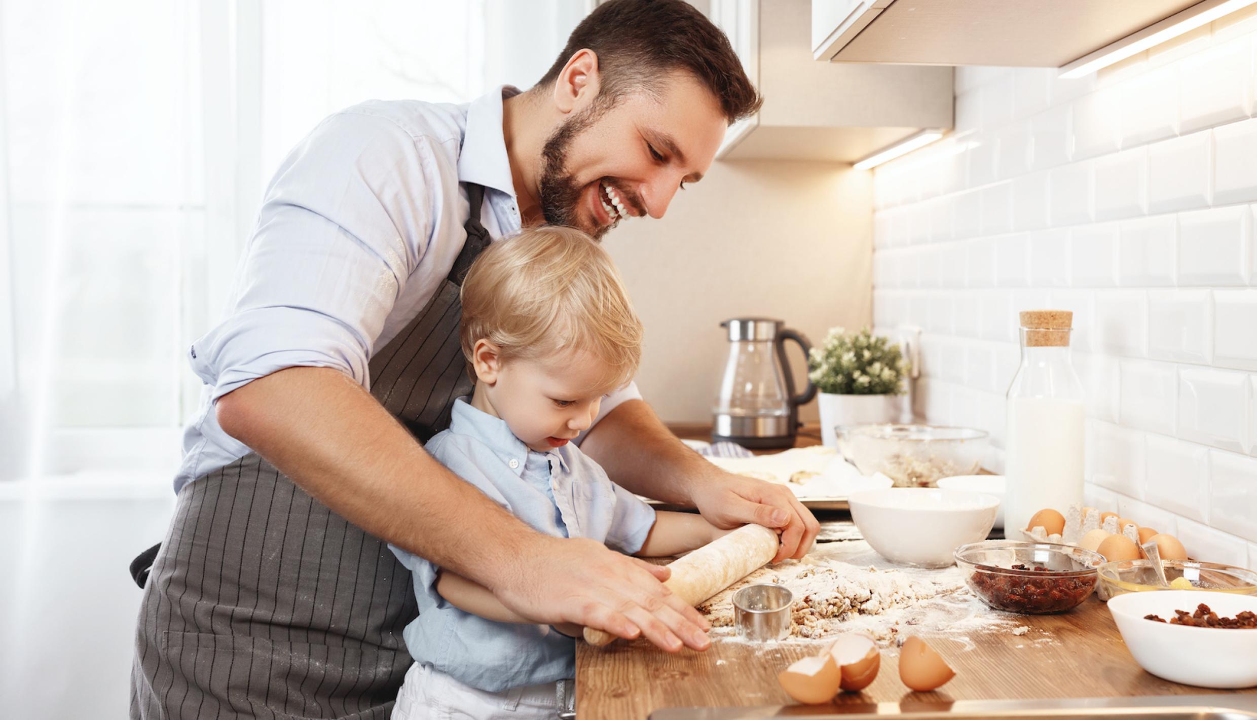 A father helping his son cook in the kitchen