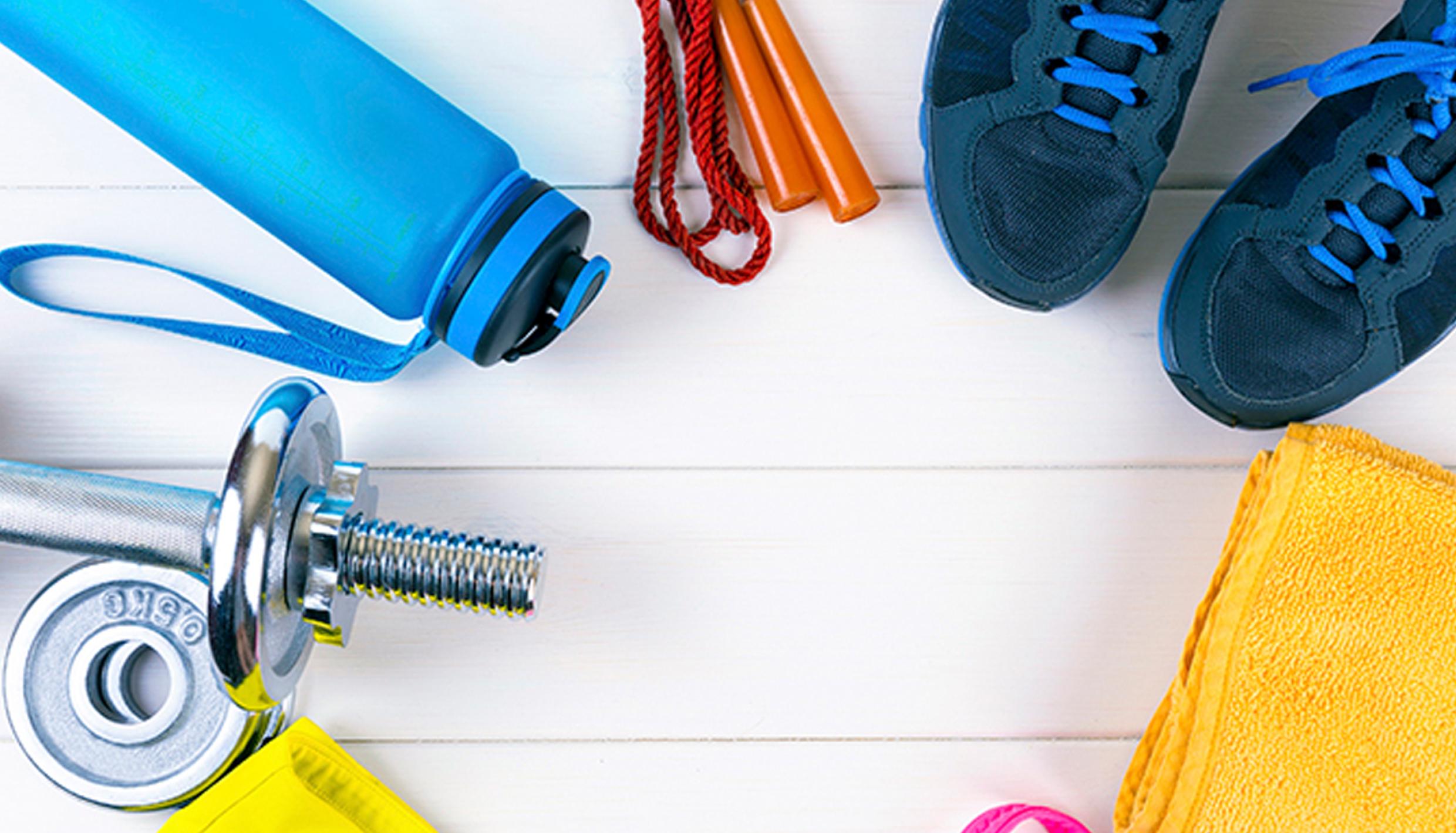 An array of workout items, such as a barbell, water bottle, jumprope, yoga mat, and sneakers