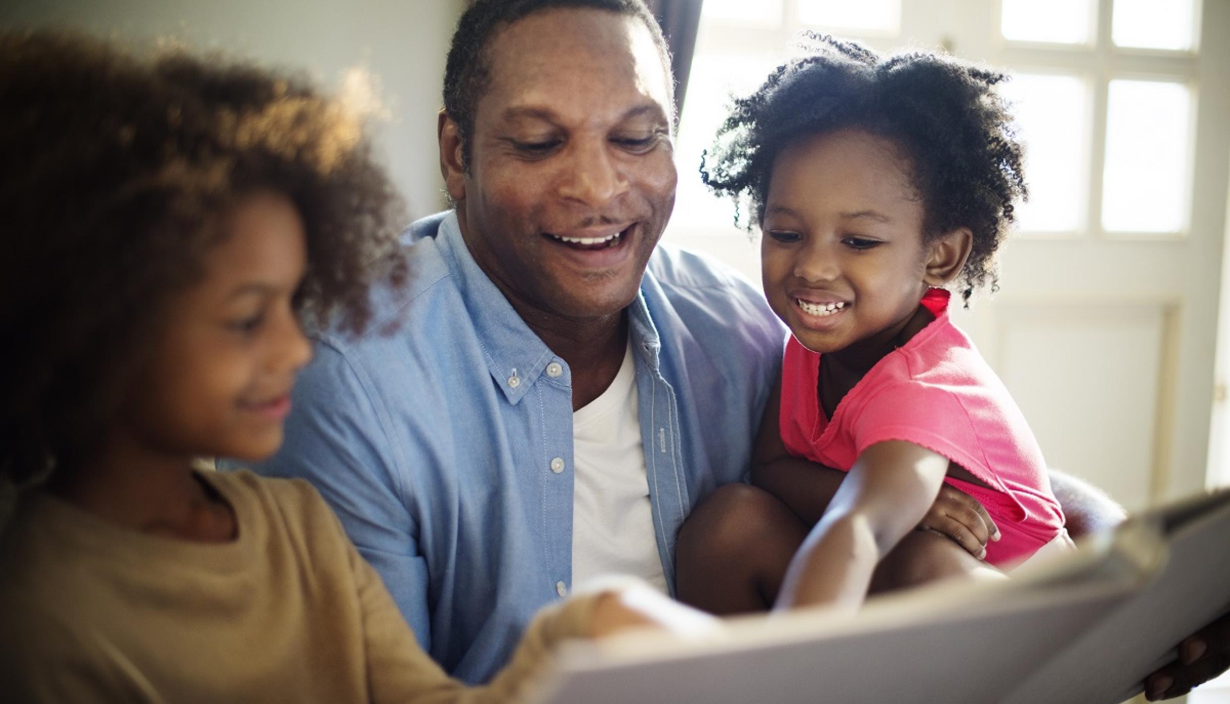 man reading to daughters