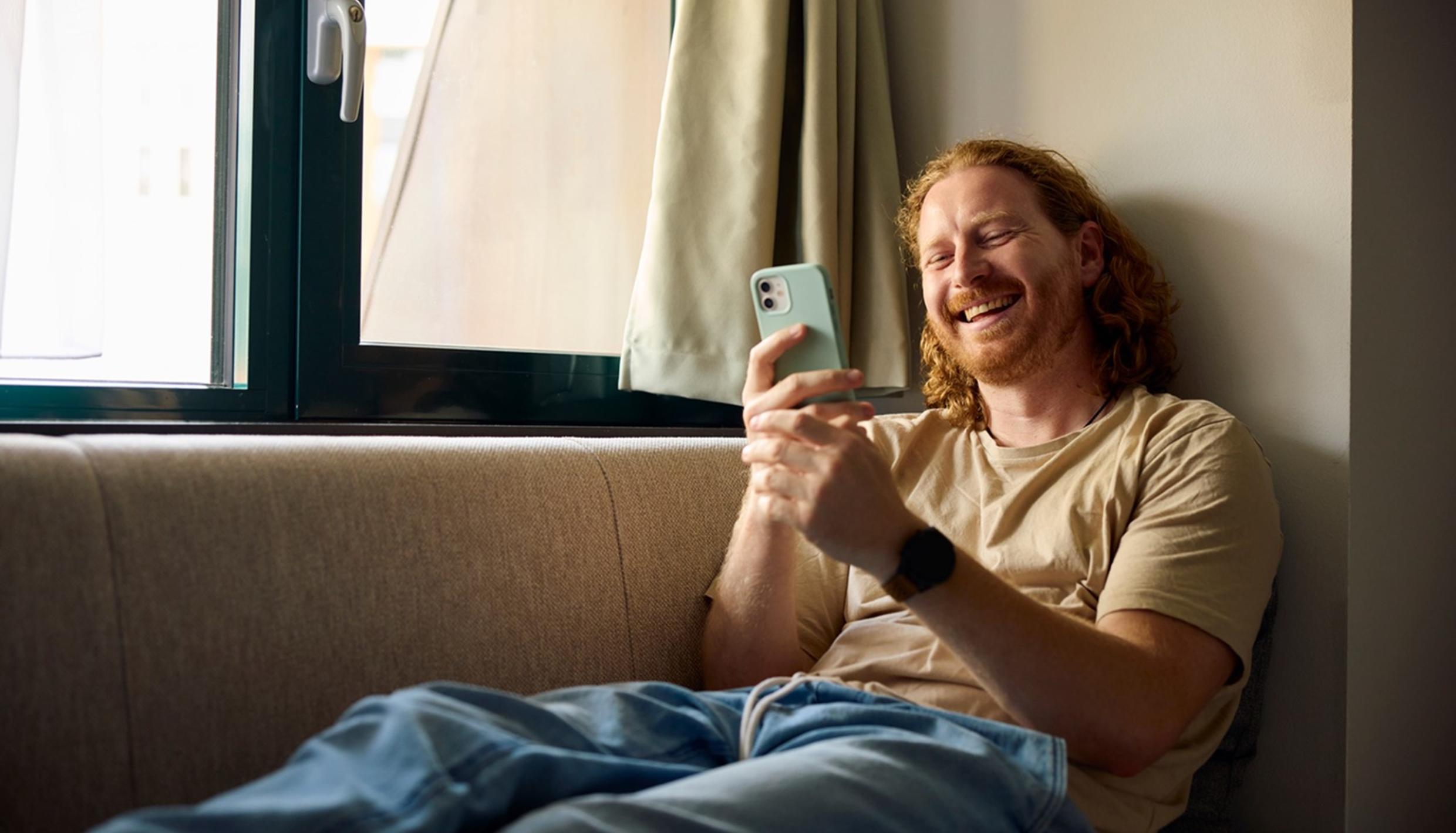 Un hombre sonriendo a su teléfono.
