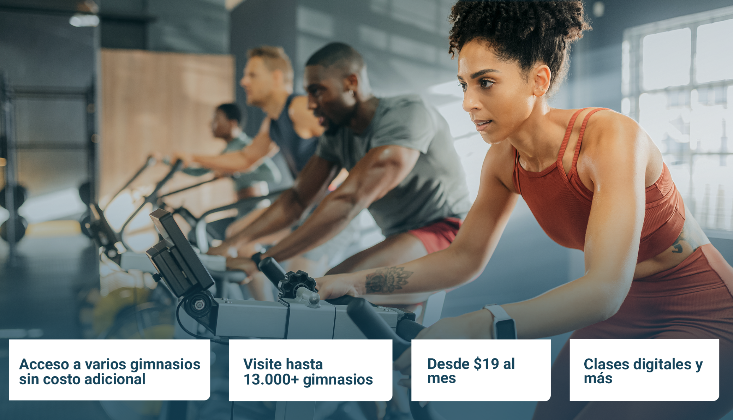 Cuatro personas en el gimnasio en bicicletas de spinning.