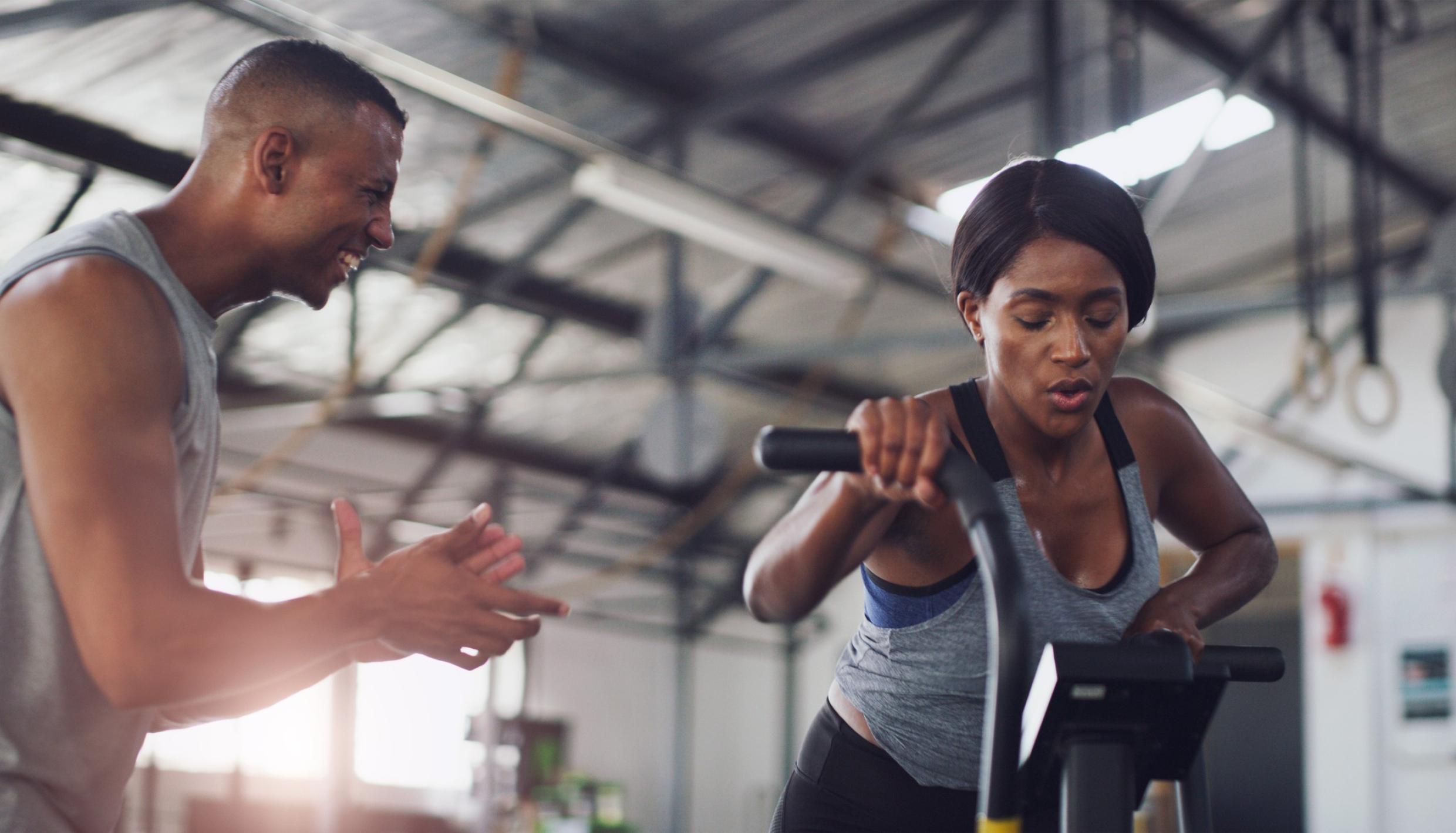 Woman in gym with trainer exercising on bike