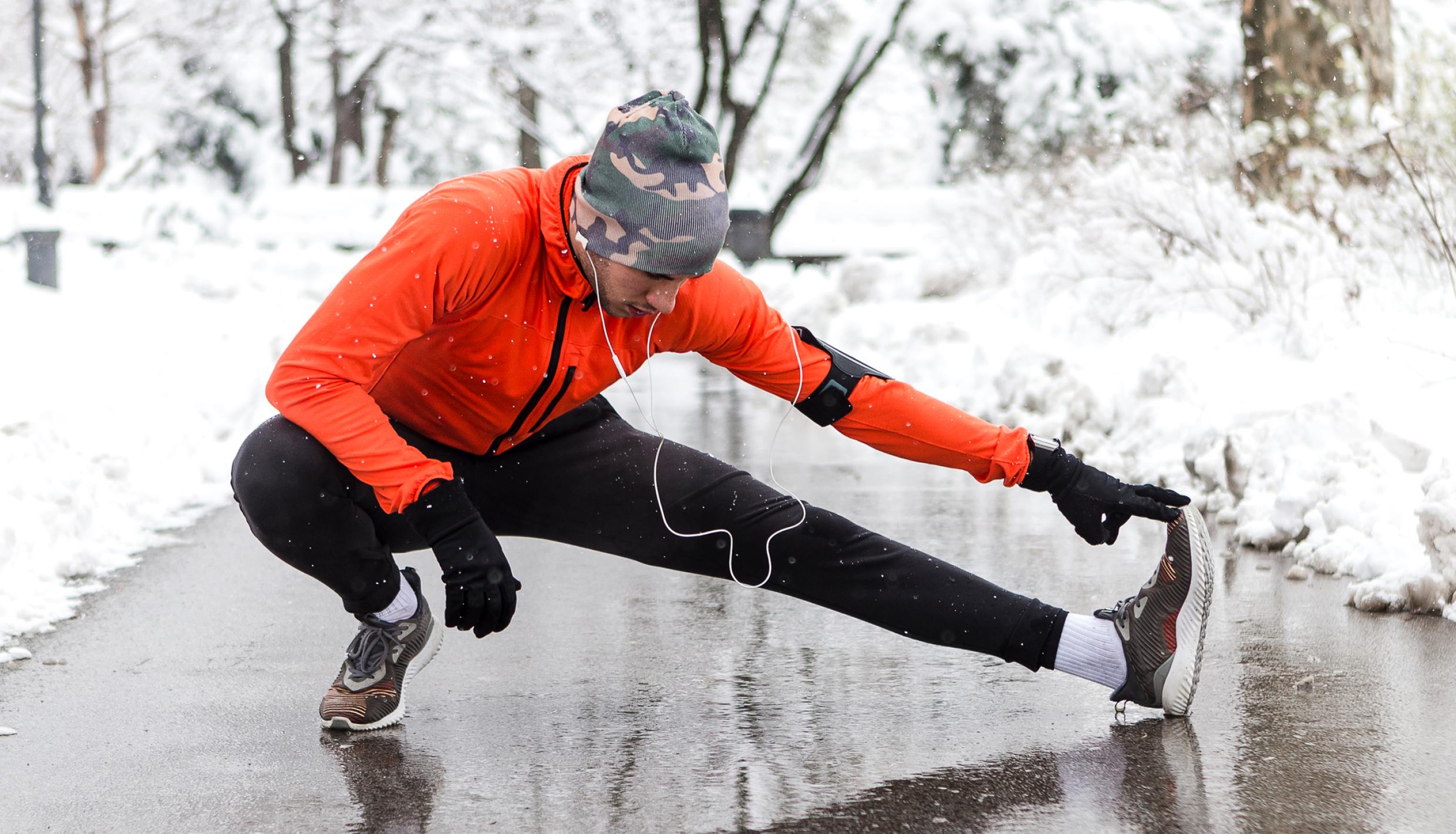 man outside stretching in winter workout clothes