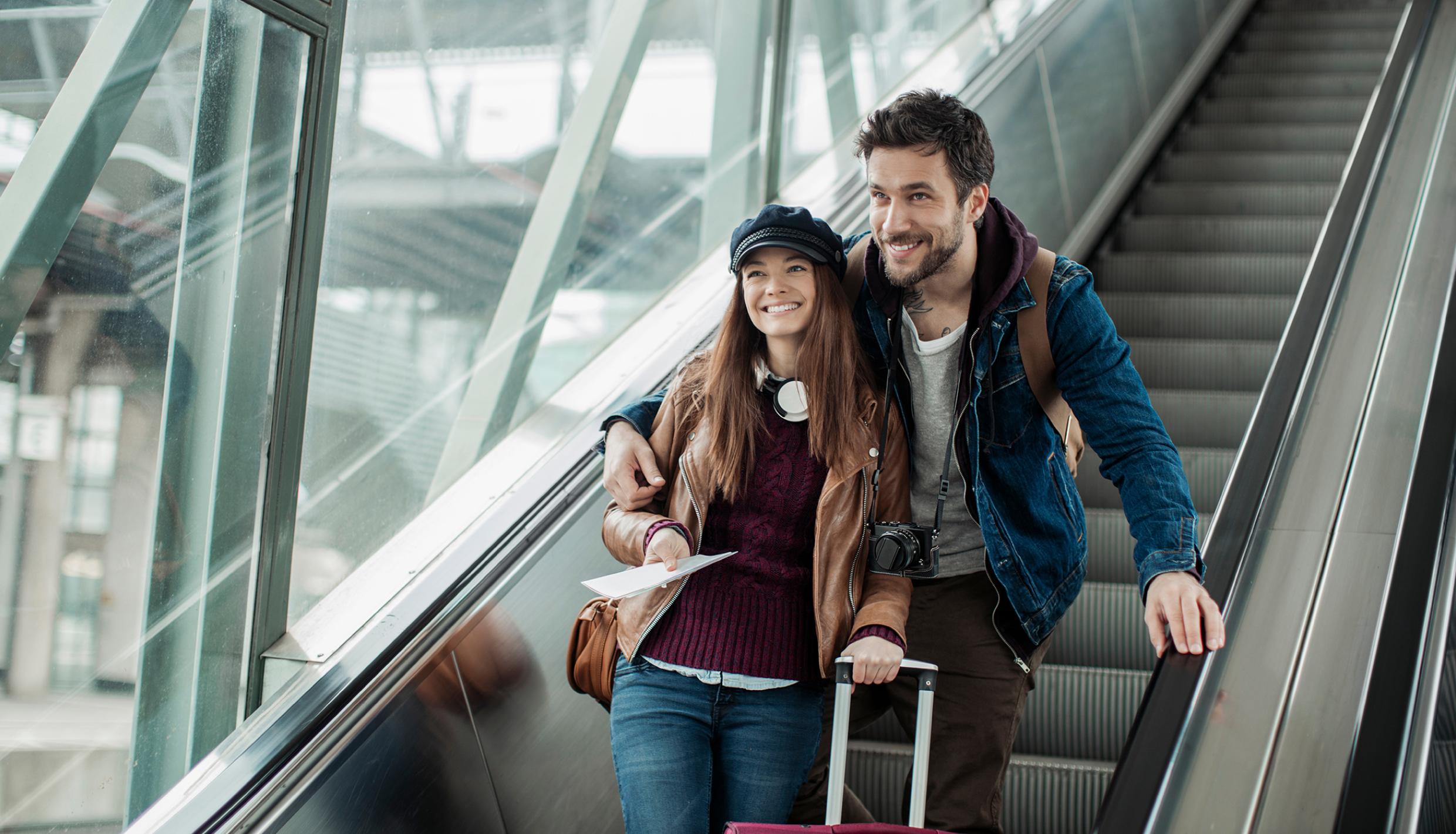 man and women going down on escalator and holding a bag