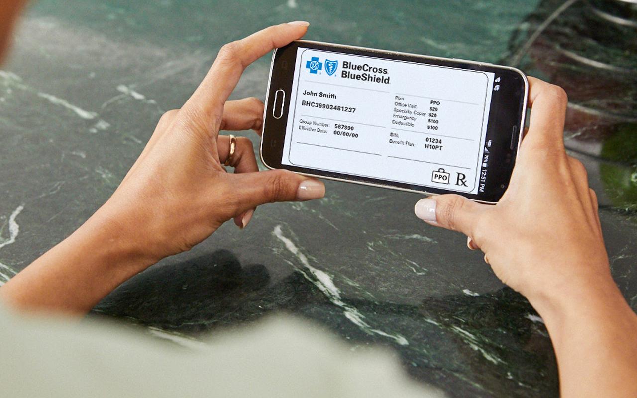 Person holding a smartphone with a picture of their insurance card displayed