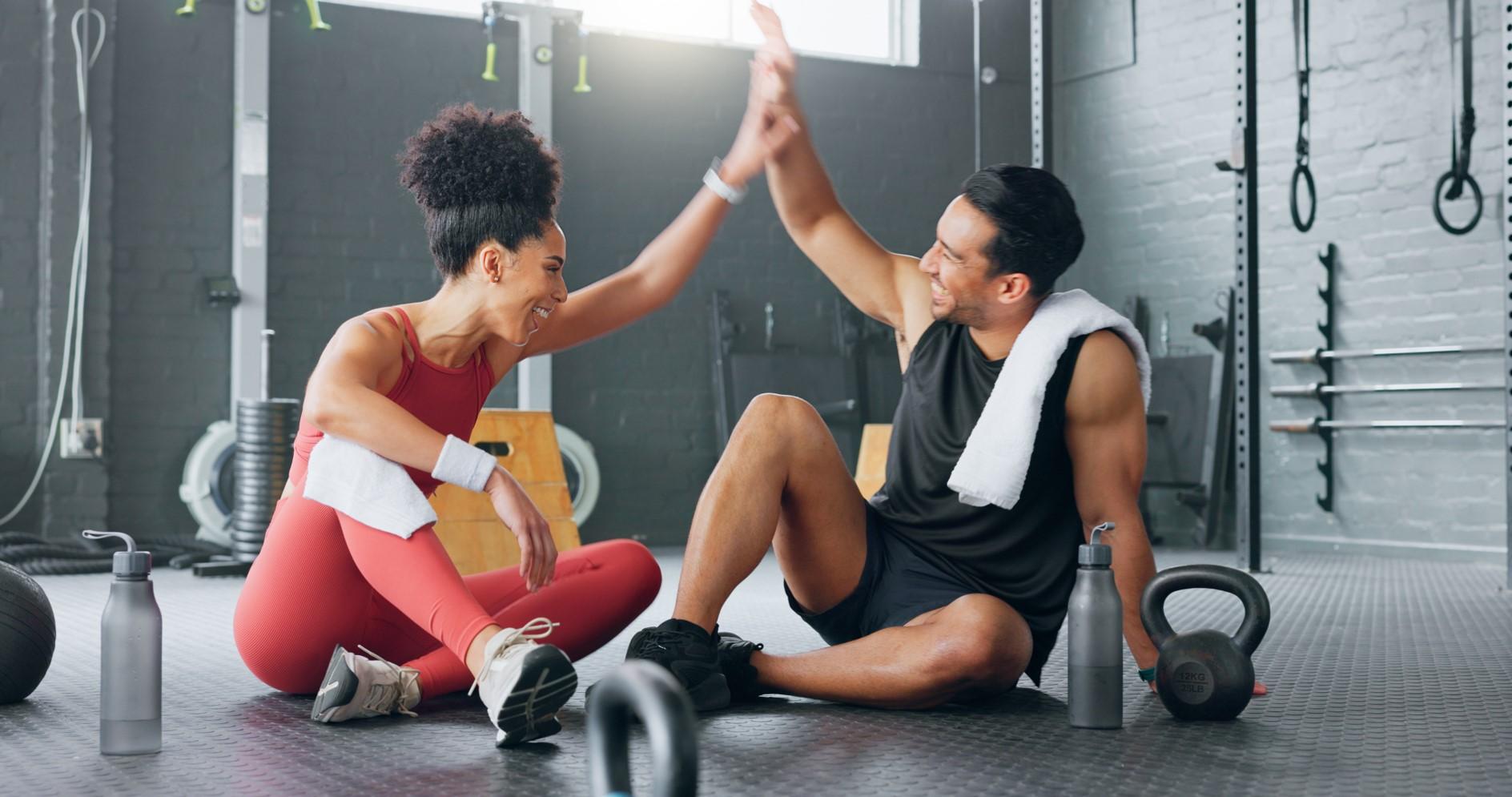man and woman high fiving at gym