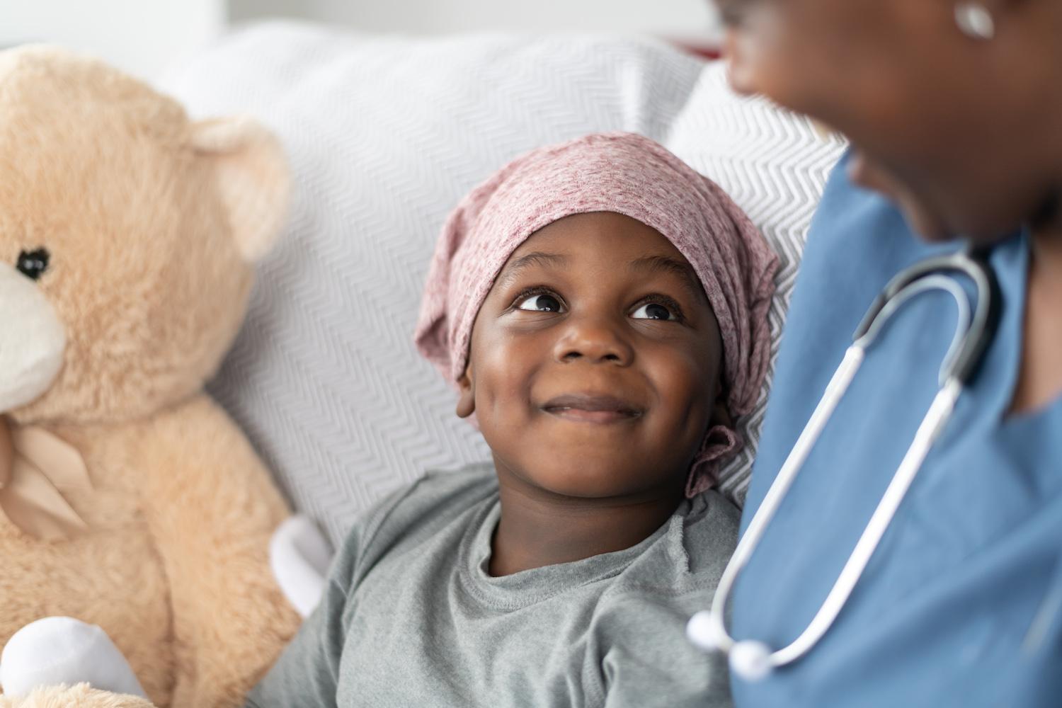 A young child in a hospital smiling up at their nurse.