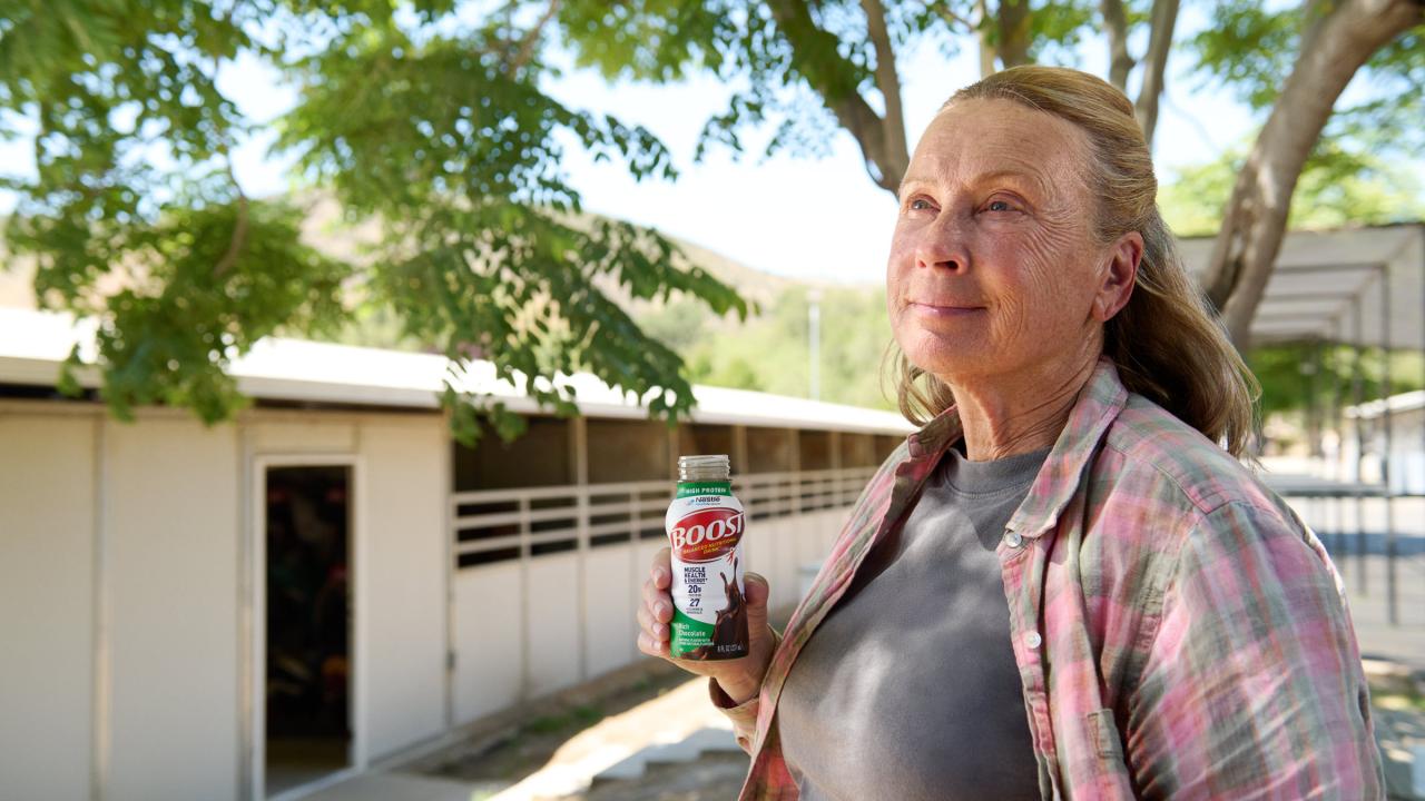 Mujer de pie al aire libre sosteniendo un batido Boost