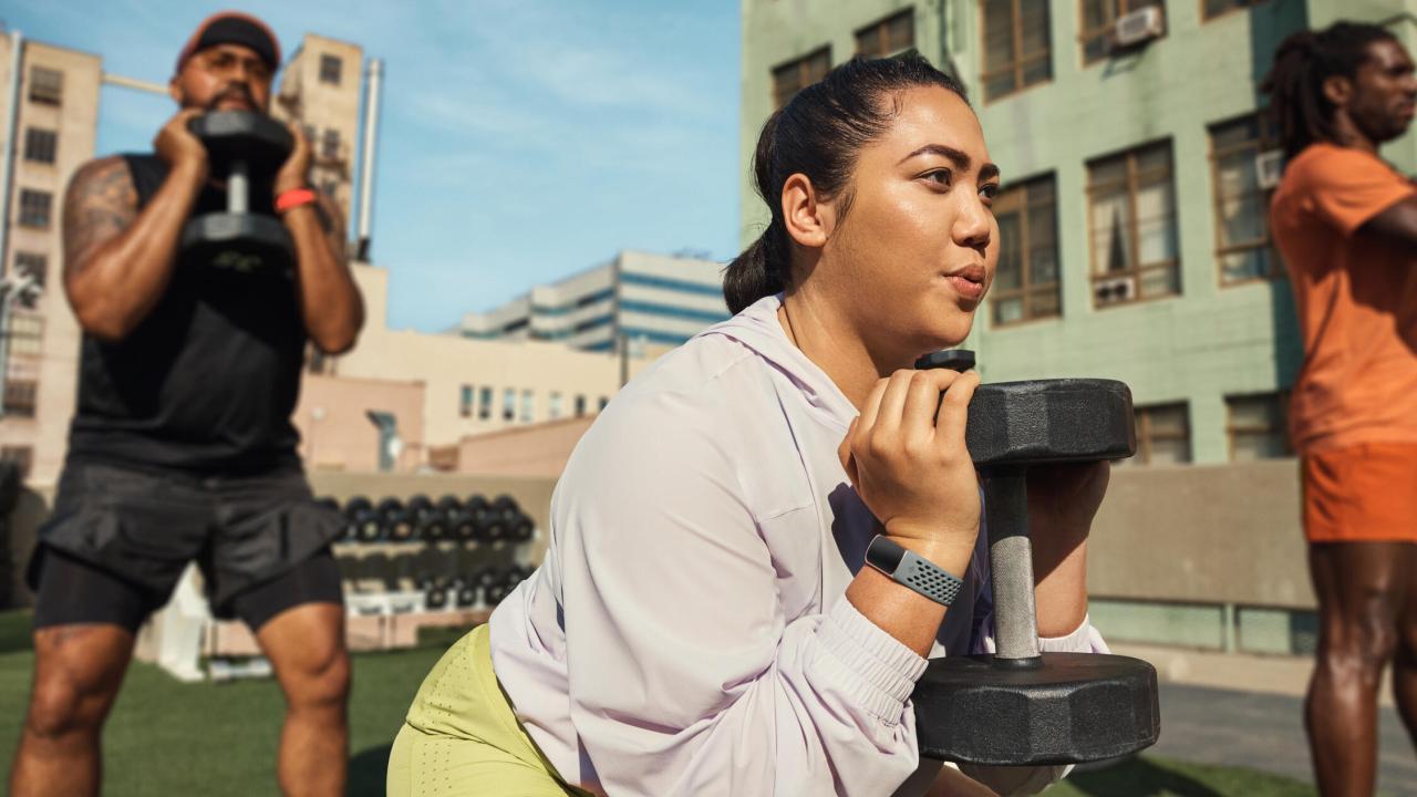 three people lifting weights on rooftop