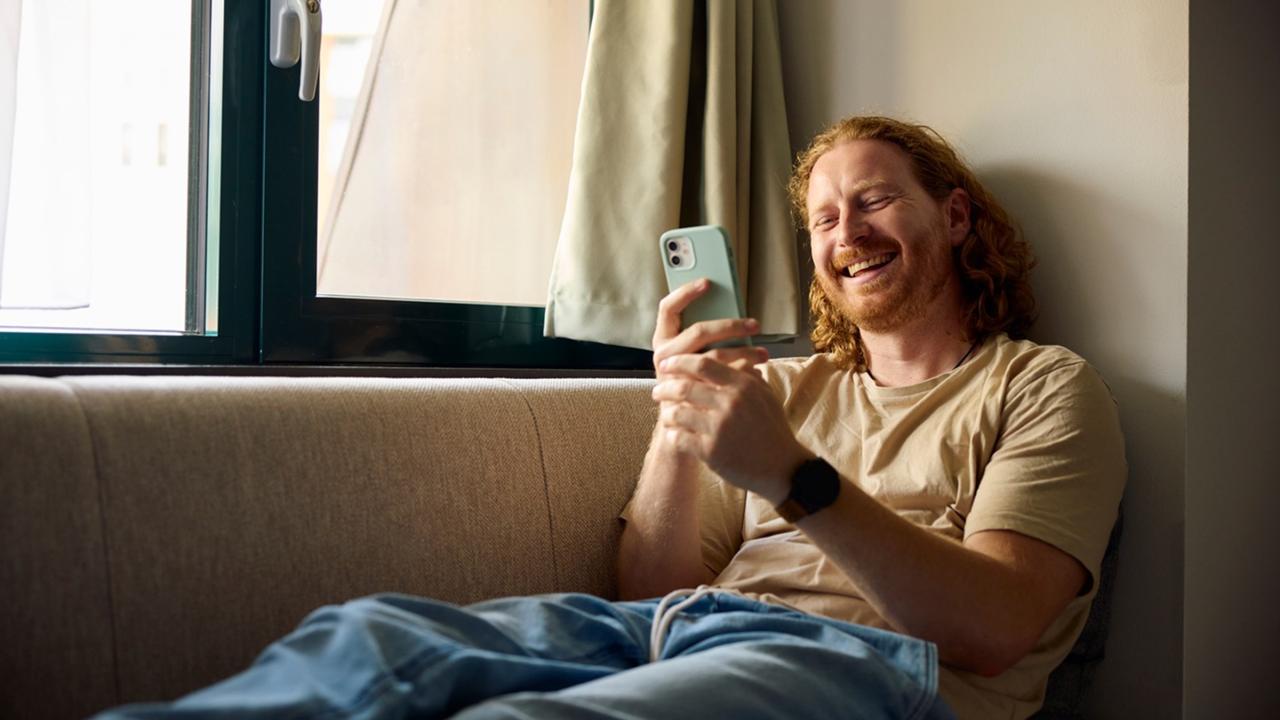 Un hombre sonriendo a su teléfono.