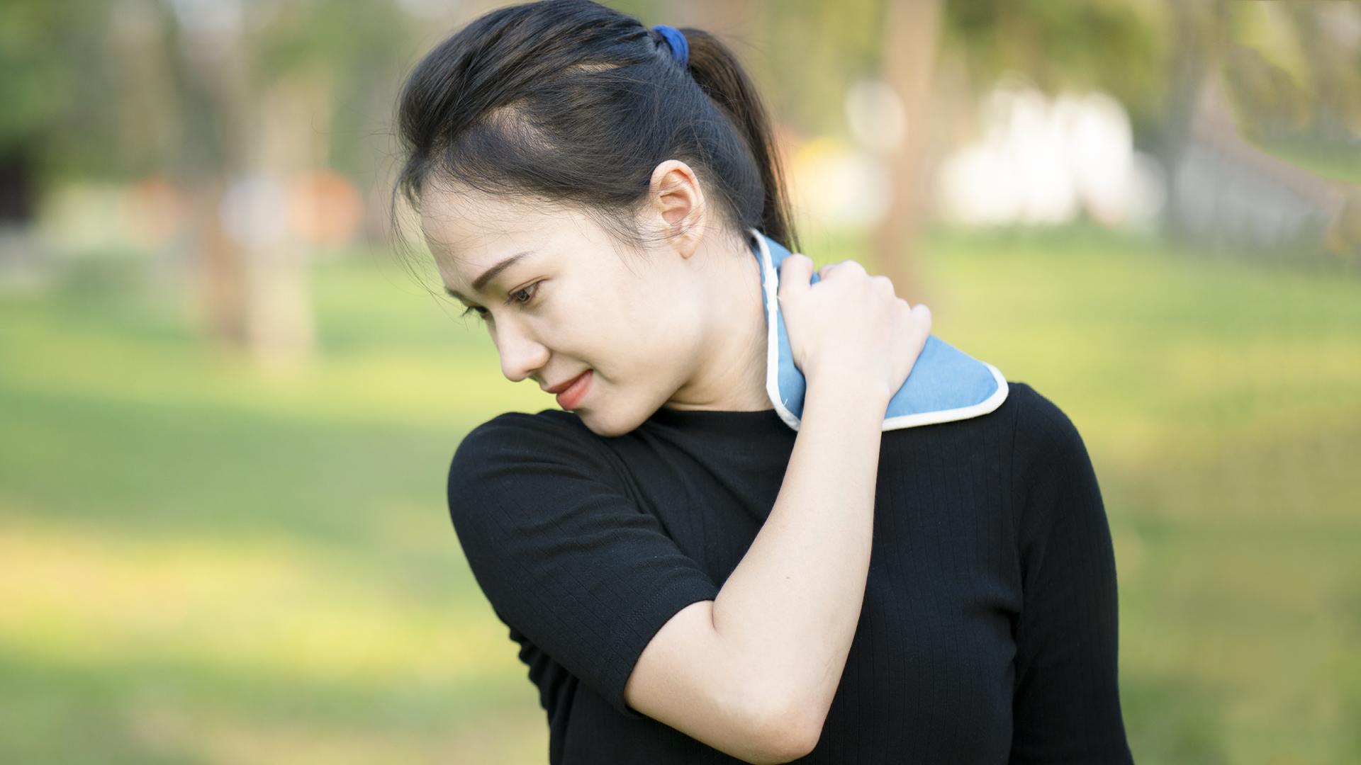 woman holding heat pack to neck