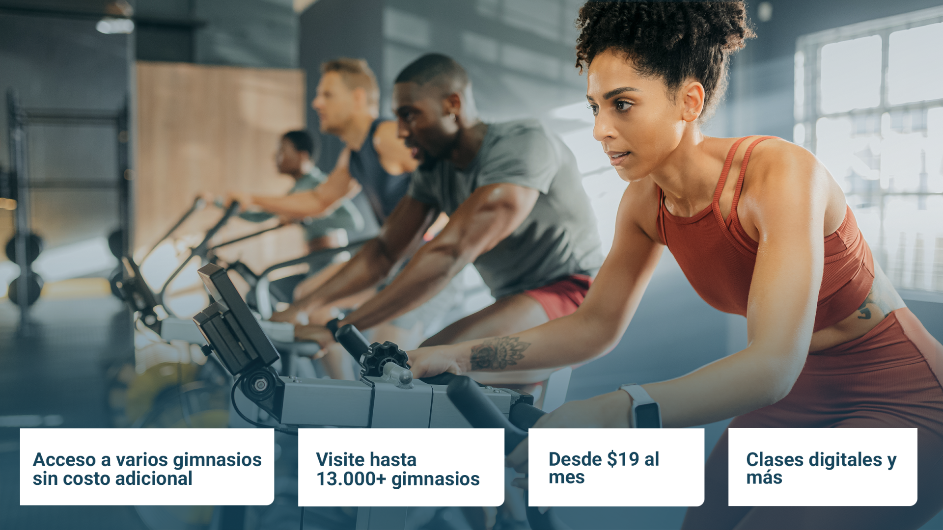 Cuatro personas en el gimnasio en bicicletas de spinning.