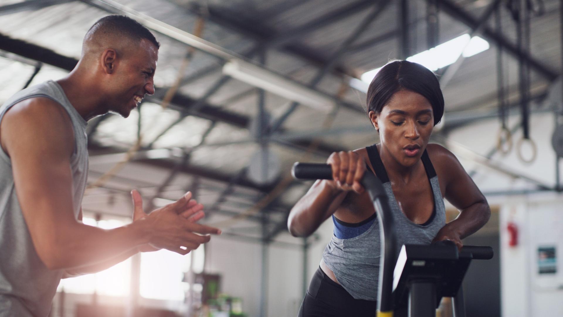 Woman in gym with trainer exercising on bike
