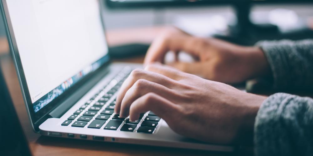 Manos escribiendo en una computadora portátil