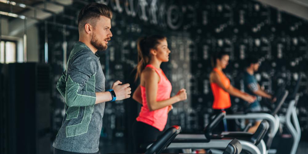 Cuatro personas corriendo en cintas de correr en un gimnasio