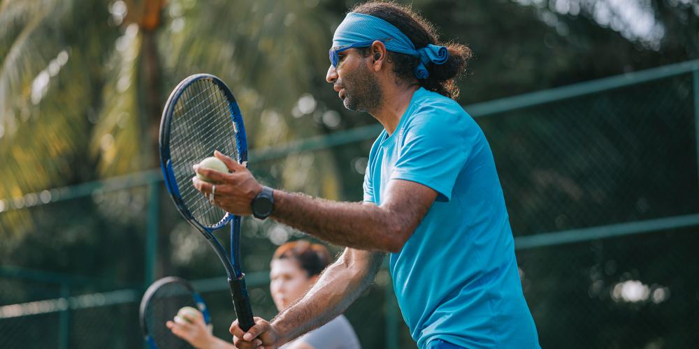 hombre jugando tennis usando un audifono