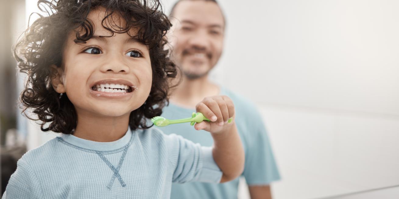 nino limpiandose los dientes con su papa mirando