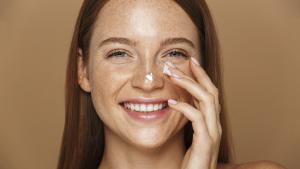 Woman applying skin cream to face