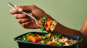 Hand holding fork and eating salad