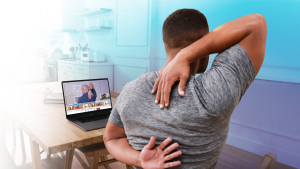 man stretching his back while watching laptop