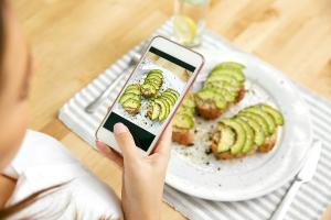 Una persona tomando una foto de un plato de tostadas con aguacate.